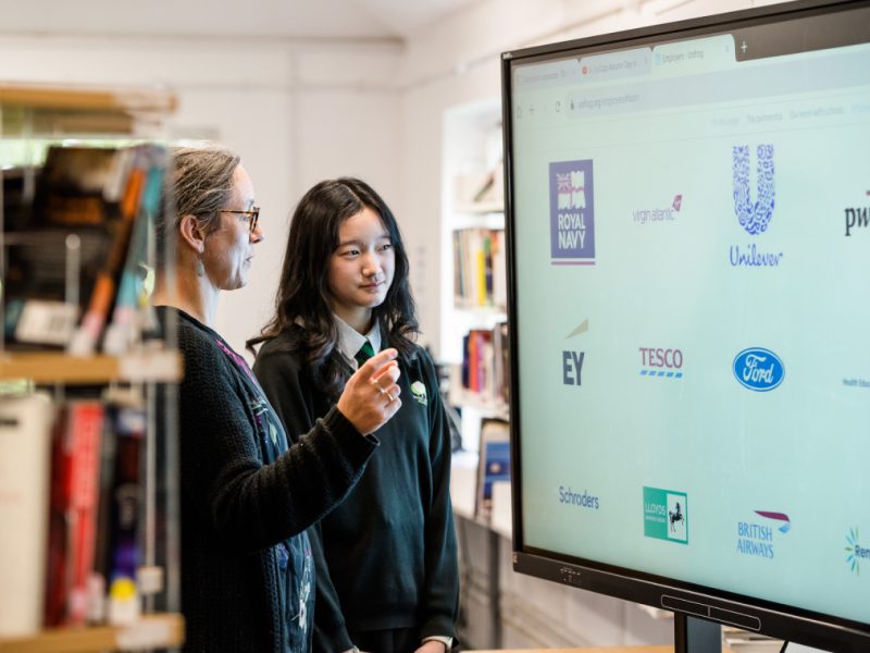 Student and teacher looking at a screen showing various brand logos