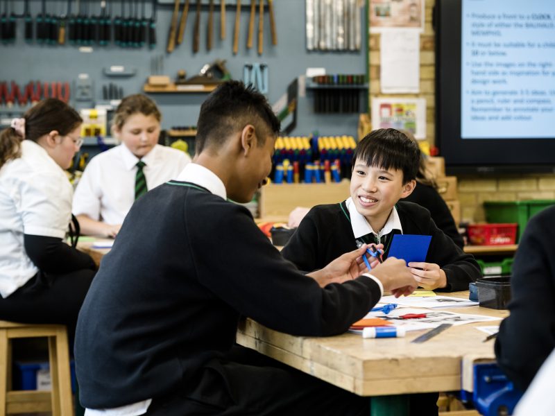 Two students sat at a desk talking and smiling
