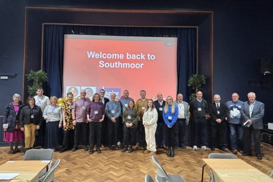 Southmoor Academy staff and alumni in an assembly room in front of a screen that says 'Welcome back to Southmoor'