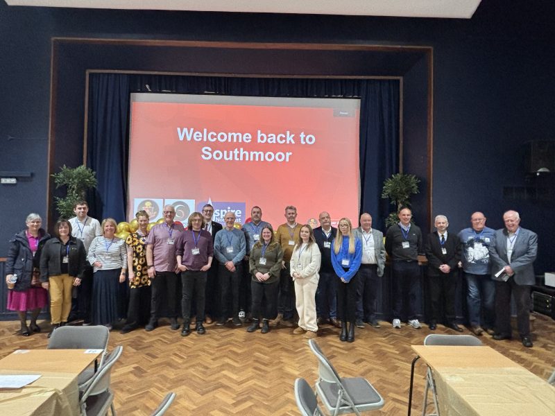 Southmoor Academy staff and alumni in an assembly room in front of a screen that says 'Welcome back to Southmoor'