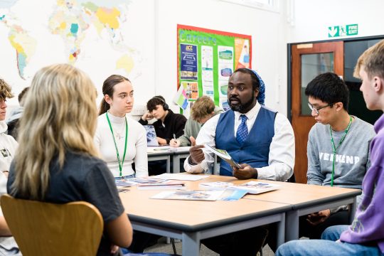 A careers leader talking to students at a table in a classroom