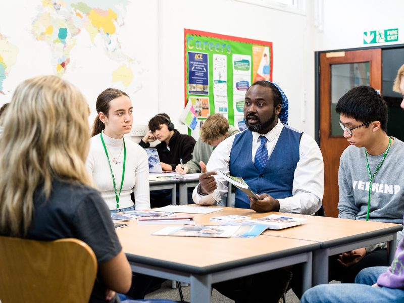 A careers leader talking to students at a table in a classroom